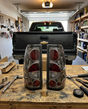 Pair of smoked Silverado tail lights on a garage workbench